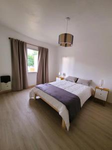 Un dormitorio con una cama grande y una ventana en Casita Catalejo Travel, en Puerto Madryn