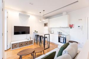 ein Wohnzimmer und eine Küche mit einem Sofa und einem Tisch in der Unterkunft Wonderful Duplex W Private Patio & AC by LovelyStay in Porto