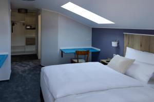 1 dormitorio con cama blanca y pared azul en Hotel Brasserie Chaussee en Seeheim-Jugenheim