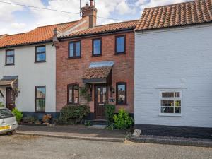 a red brick house with a white garage at Nightingale Cottage in Castle Acre