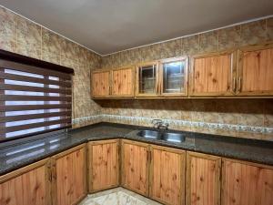a kitchen with wooden cabinets and a sink at Sultan Home in Wadi Musa
