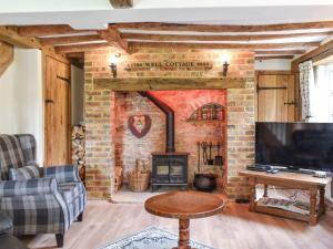 a living room with a brick fireplace and a tv at Well Cottage in Itchingfield