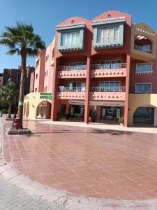 a pink building with a palm tree in front of it at Hurghada Marina in Hurghada