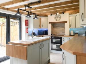 a kitchen with white cabinets and a sink at Well Cottage in Itchingfield
