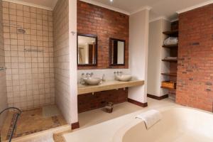 a bathroom with two sinks and a brick wall at The Jasper House 73 in Mabula