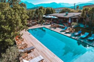 an aerial view of a resort pool with lounge chairs at Le Maquis Plage Corse in Poggio-Mezzana