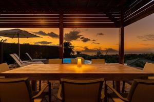 a wooden table with chairs and an umbrella on a patio at Magnificent 5 Br Villa with pool: amazing views in Punaauia