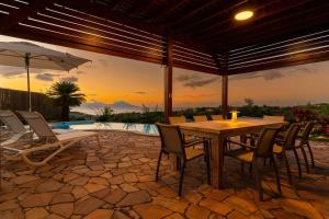 a patio with a table and chairs and a pool at Magnificent 5 Br Villa with pool: amazing views in Punaauia