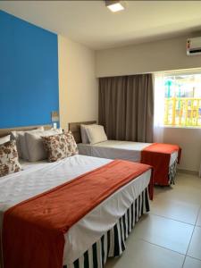 a hotel room with two beds and a window at Resort Ondas Praia apart in Porto Seguro