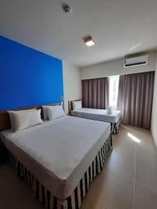 2 camas en una habitación de hotel con una pared azul en Resort Ondas Praia apart, en Porto Seguro