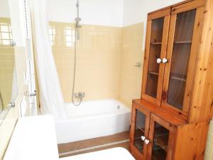 a bathroom with a tub and a shower and a wooden cabinet at Loue maison 10 couchages à La Rochelle avec jardin, proche plage in La Rochelle