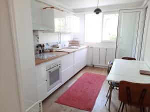 a kitchen with white cabinets and a table with a pink rug at Loue maison 10 couchages à La Rochelle avec jardin, proche plage in La Rochelle +8 photos