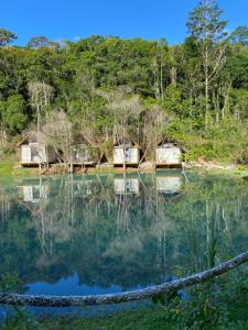 un grupo de cabañas sentadas en la cima de un lago en Chalés da Floresta, en Porto Seguro