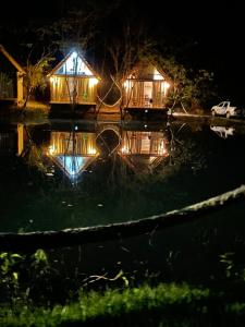 un par de casas en el agua por la noche en Chalés da Floresta, en Porto Seguro