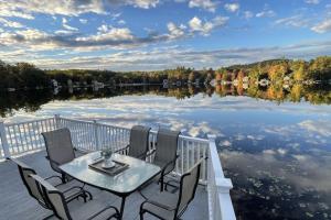 un tavolo e sedie seduti su una terrazza accanto a un lago di Waterfront Cottage and Ski Getaway! a Sunapee