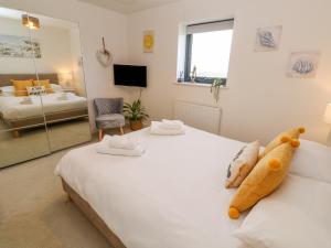 a bedroom with a large white bed and a living room at 11 Seaquest in Newquay