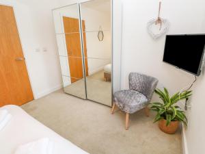 a bedroom with a mirror and a chair and a tv at 11 Seaquest in Newquay