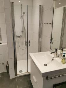 een witte badkamer met een douche en een wastafel bij FeWo Nordsee-Perle Meerblick - Horumersiel in Horumersiel