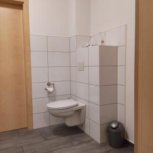 a white bathroom with a toilet and a trash can at Am Wiesengrund in Lebus