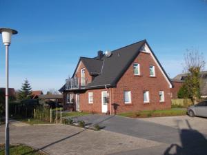 une grande maison en briques rouges avec un toit noir dans l'établissement FeWo Goldene Linie, à Wangerland