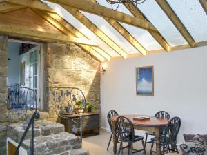 a patio with a table and chairs and a wooden ceiling at Wallhouse Barn in Blisland