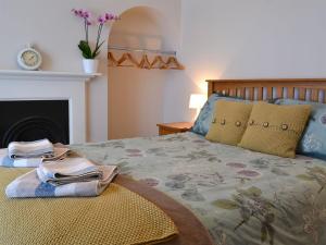 a bedroom with a bed and a fireplace at Melrose Cottage in Cromer