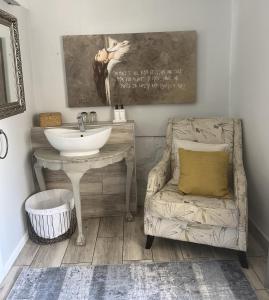 een badkamer met een wastafel, een stoel en een spiegel bij C-Vu-Cottage cosy and warm private apartment in Mosselbaai