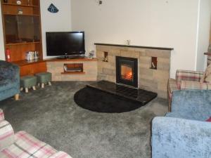 a living room with a fireplace and a tv at Oyster Catcher in Embo