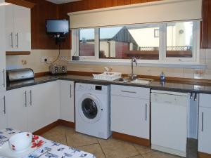 a kitchen with a washing machine and a sink at Oyster Catcher in Embo