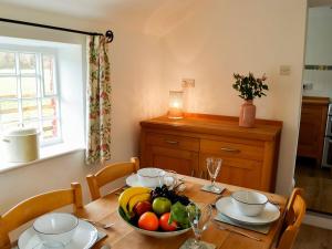 The Cottage At 1710 في Castle Carrock: طاولة غرفة الطعام مع وعاء من الفواكه عليها