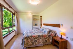 a bedroom with a bed and a table and a window at Reserva Imbassaí - Casa C02 Orquídeas in Imbassai