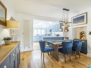 a kitchen with a dining table and blue chairs at The Wicket in Newton Ferrers