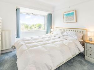 a white bed in a bedroom with a window at The Wicket in Newton Ferrers