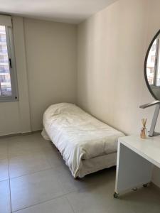 Habitación blanca con cama y espejo en en Nueva Córdoba alojamiento para 3 personas en Córdoba