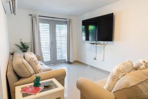 a living room with two chairs and a tv at Aquaville Dorado Moderna Villa 2 in Dorado