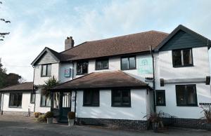 a white house with black windows and a roof at Burton Lodge Guest House & Spa in Brandesburton