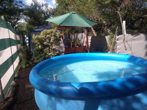 una piscina azul con sombrilla en el patio trasero en Cabaña en las sierras de Cosquín PB en Cosquín