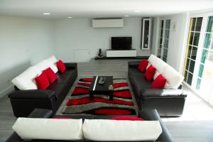 soggiorno con divano nero e cuscini rossi di Casa Madeira a Santa Cruz