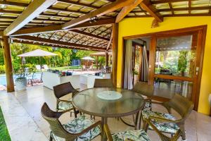 un patio con mesa, sillas y piscina en Reserva Imbassaí - Casa C02 Orquídeas, en Imbassai