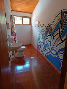 Baño con 2 lavabos y una pintura en la pared en Cataratas Jazz Hostel en Puerto Iguazú