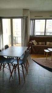 een woonkamer met een tafel en stoelen en een bank bij Beau studio cabine avec balcon, vue piscine, parking privé, climatisation, solarium, laverie in Cap d'Agde