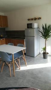 een keuken met een tafel en stoelen en een koelkast bij Beau studio cabine avec balcon, vue piscine, parking privé, climatisation, solarium, laverie in Cap d'Agde