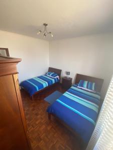 サンタ・クルーズにあるCasa Madeiraのブルーシーツ付きの客室内のベッド2台