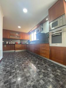 a large kitchen with wooden cabinets and a tile floor at Casa Madeira in Santa Cruz