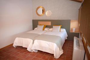 TorrellesにあるCasa Rural Hospital de las Palabrasのベッドが2つあり、壁に鏡がある寝室