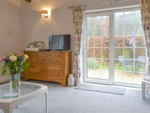 a living room with a tv and a glass table at Clinton Cottage in Yaxham