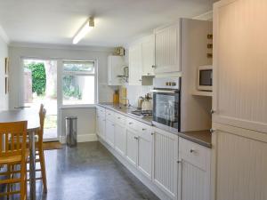 a kitchen with white cabinets and a stove top oven at Trelawny Court in Saint Minver