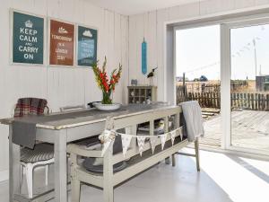 ein Esszimmer mit einem Tisch und einer Bank in der Unterkunft Gull House in Dungeness
