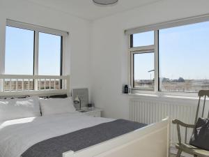 ein weißes Schlafzimmer mit einem Bett und zwei Fenstern in der Unterkunft Gull House in Dungeness