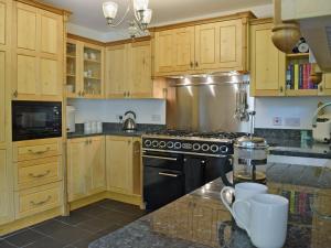 a kitchen with wooden cabinets and a black stove top oven at Cornant in Llechryd